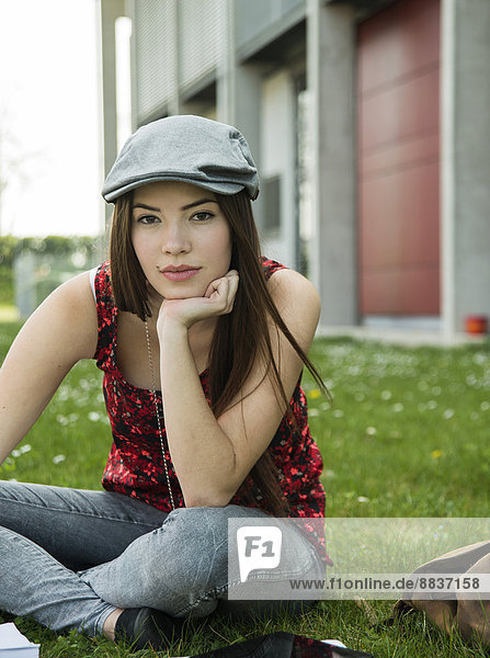 Brunette young woman sitting on meadow