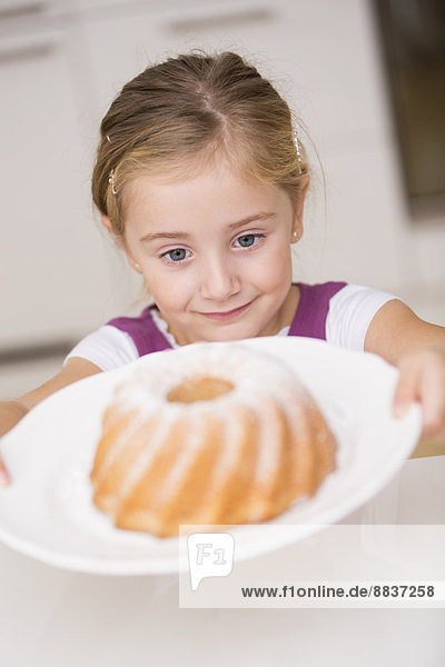 Porträt eines lächelnden kleinen Mädchens mit Teller und Ringkuchen