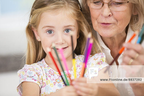 Seniorin und Enkelin mit Buntstiften