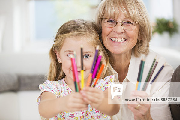 Senior woman and granddaughter showing coloured pencils
