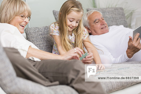 Senior woman and granddaughter playing together on sofa in living room