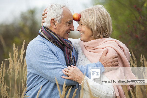 Porträt eines glücklichen Seniorenpaares mit Apfelspaß
