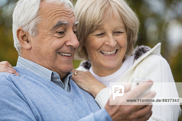 Porträt eines lächelnden älteren Paares  das sich auf dem Smartphone selbst porträtiert.