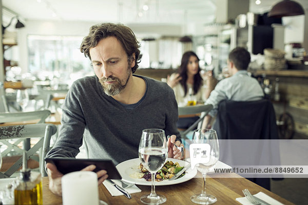 Erwachsener Mann mit digitalem Tablett im Restaurant