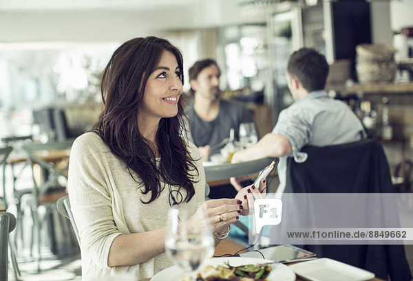 Lächelnde Geschäftsfrau mit Handy im Restaurant