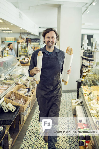 Porträt eines reifen Bäckers mit Brotlaiben im Supermarkt
