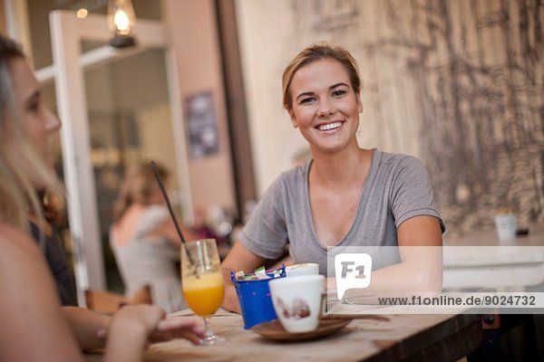 Zwei junge erwachsene Freundinnen beim Plaudern im Café
