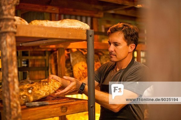 Reifer Mann stellt frisches Brot ins Regal