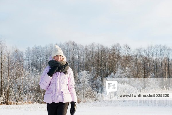 Mid adult woman wearing winter clothing in snow covered field