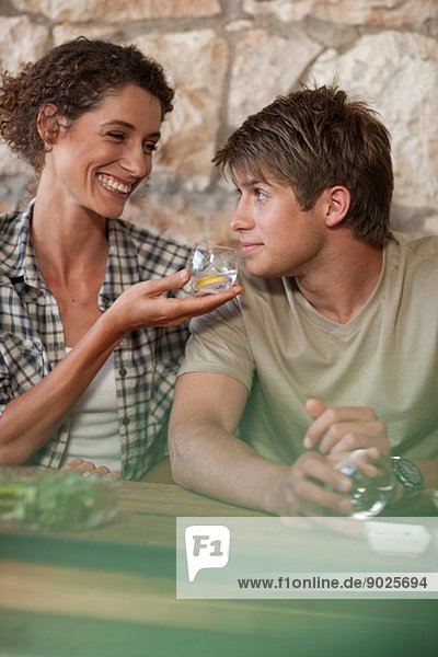 Mann und Frau sitzen am Tisch und probieren Getränke.