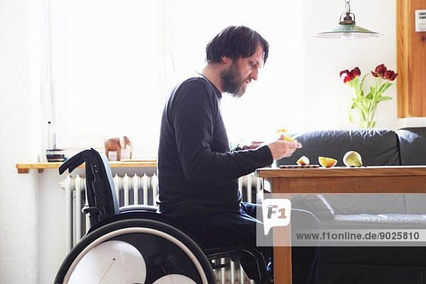 Mann im Rollstuhl beim Obstschneiden