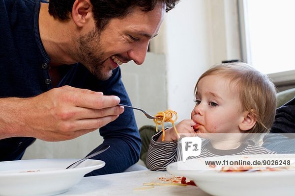 Vater füttert eine einjährige Tochter Spaghetti