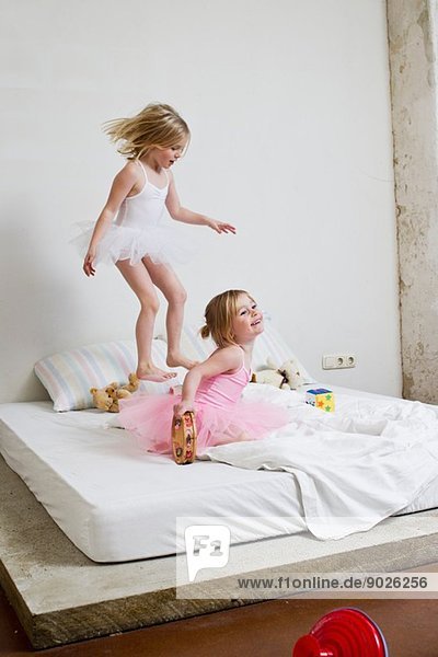 Zwei junge Schwestern als Balletttänzerinnen  die auf dem Bett spielen.