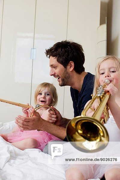 Vater und zwei junge Töchter beim Musizieren