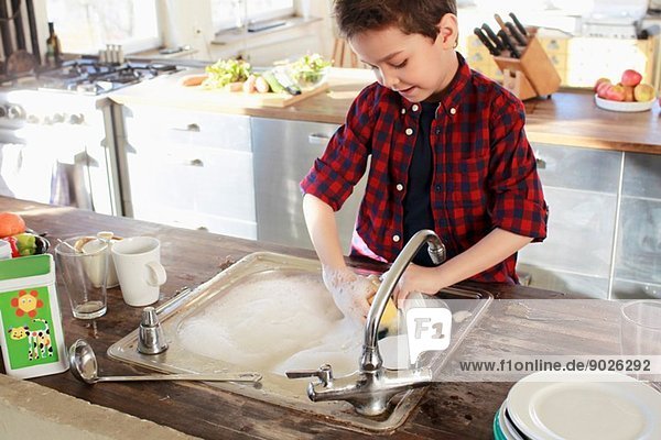 Kleiner Junge beim Abwaschen in der Küche