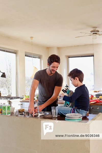 Father and young son clearing up in kitchen