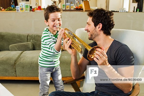 Vater ermutigt jungen Sohn beim Trompetenspiel
