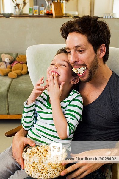 Vater und junger Sohn mit Popcorn im Mund