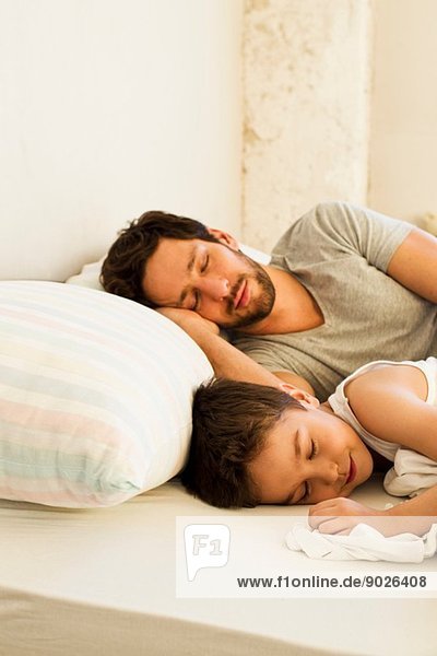 Vater und kleiner Sohn schlafen im Bett.