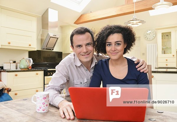 Porträt eines Paares mit Laptop auf dem Küchentisch