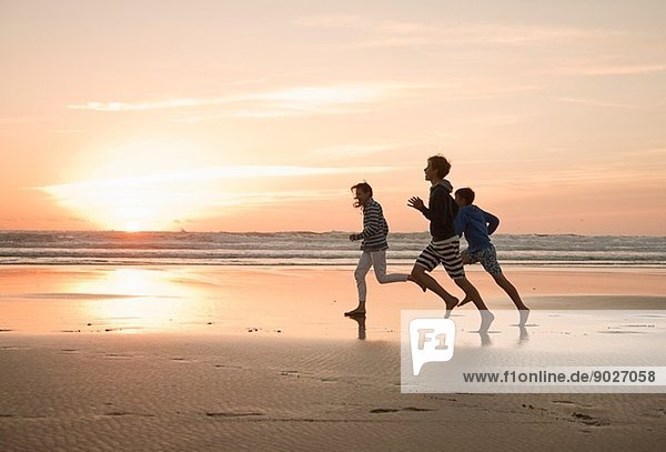 Mutter und Söhne die am Strand laufen