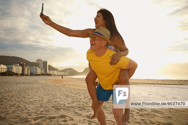 Couple taking self portrait on smartphone  Copacabana beach  Rio De Janeiro  Brazil