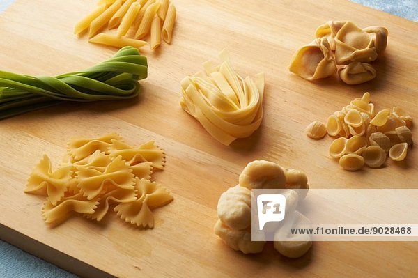 Still life of chopping board with a variety of raw pasta