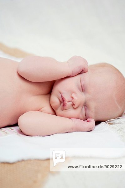 Baby asleep with hands beside face