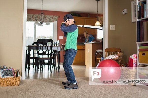 Porträt eines Jungen  der im Wohnzimmer Baseball übt.
