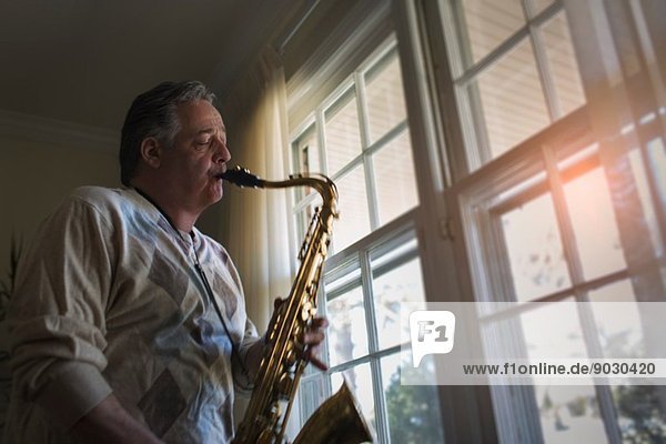 Erwachsener Mann zu Hause beim Saxophonspielen