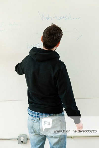 Male designer drawing on whiteboard in studio