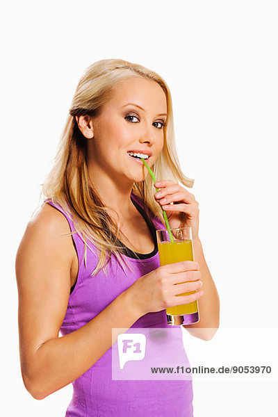 Young woman in sports clothes drinking juice  studio shot
