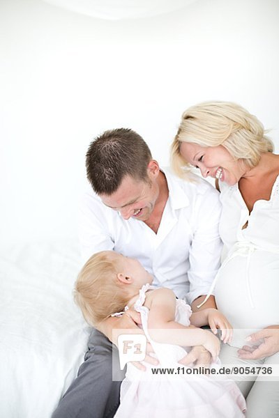 Parents playing with daughter on bed  studio shot