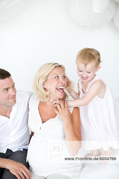 Parents playing with daughter on bed  studio shot