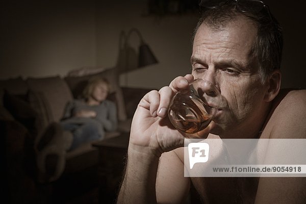 Mature man drinking woman on sofa on background