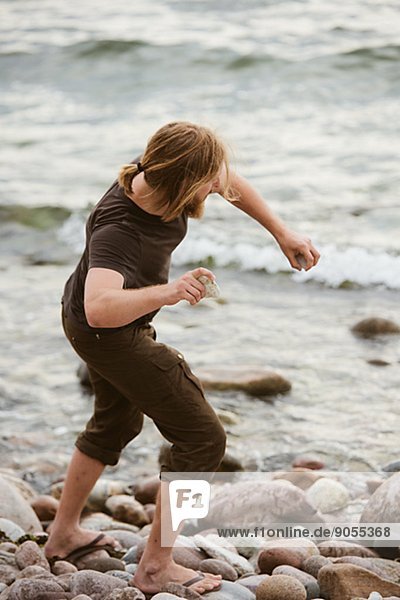 Young man throwing stones on beach  Gotland  Sweden