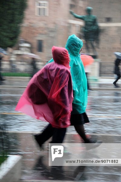 Tourists wearing plastic ponchos in rain on via dei fori imperiali street in rome italy