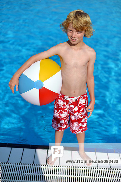 Ein Junge mit Wasserball im Freibad.