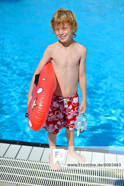 Ein Junge mit einem Badeboard im Freibad.