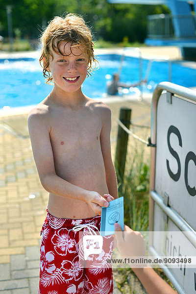 Ein Junge nimmt stolz seinen Jugendschwimmpass in einem Freibad entgegen.