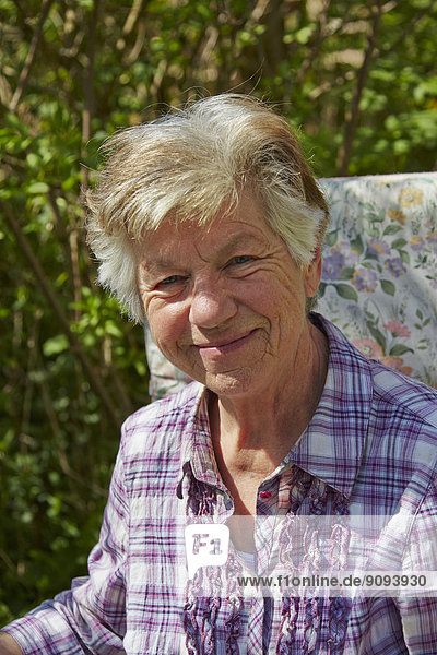 Porträt der lächelnden Seniorin im Garten