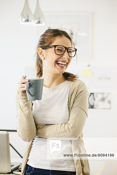 Porträt einer Frau mit Kaffeetasse im modernen Home Office