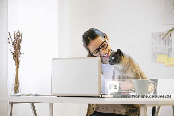Woman and her cat sitting at desk