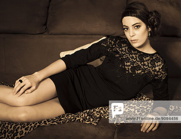 Bildnis einer jungen Frau mit schwarzem Kleidchen auf der Couch liegend