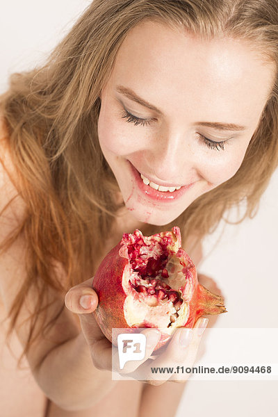 Portrait of smiling young woman eating pomegranate
