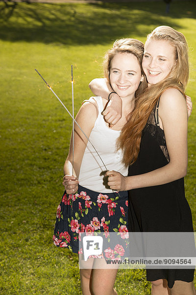 Zwei junge Freundinnen mit Wunderkerzen im Park