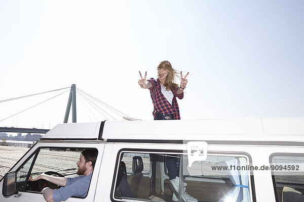 Aufgeregte Frau gestikuliert auf Minivan