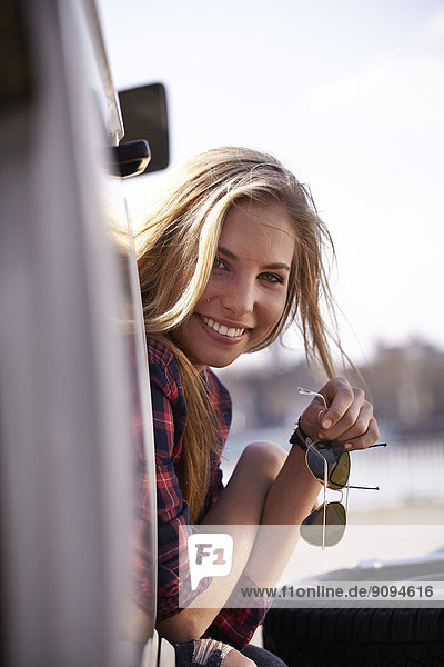 Smiling young woman looking out of minivan
