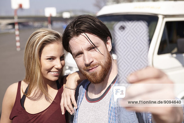 Mann nimmt Selfie mit Girlfiend vor dem Auto
