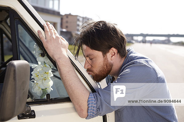Mann küsst Frontscheibe eines Autos